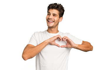 Young caucasian handsome man isolated smiling and showing a heart shape with hands.