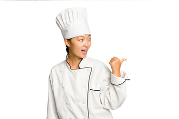 Young asian cook woman isolated points with thumb finger away, laughing and carefree.