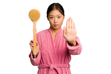 Young asian woman holding a shower brush isolated standing with outstretched hand showing stop sign, preventing you.