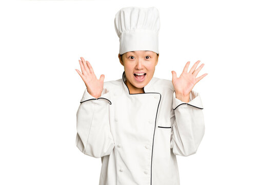 Young asian cook woman isolated receiving a pleasant surprise, excited and raising hands.