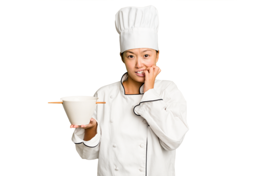 Young chef asian woman holding a bowl of ramen isolated biting fingernails, nervous and very anxious.