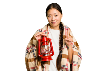 Young asian woman wearing a blanket and holding a lamp isolated showing number one with finger.