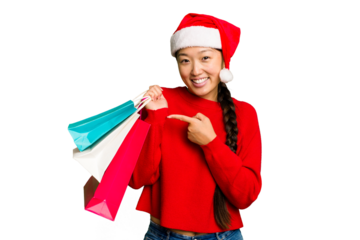 Young asian woman shopping a christmas presents isolated Young asian woman shopping a christmas presents isolated smiling and pointing aside, showing something at blank space.