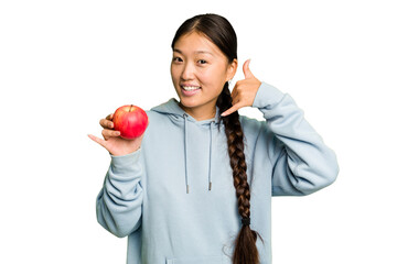 Young asian woman holding a red apple isolated showing a mobile phone call gesture with fingers.