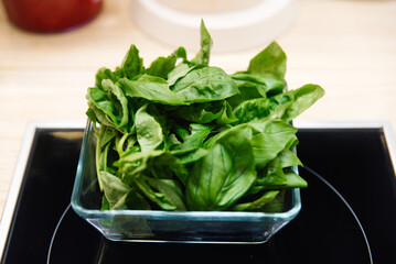 Fresh basil leaves in a glass bowl. Ingredient for the preparation of the dish.