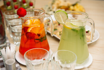 Citrus lemonades. Two pitchers of homemade lemonades. Lime slices, mint leaves, orange slices and strawberries.