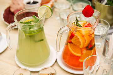 Citrus lemonades. Two pitchers of homemade lemonades. Lime slices, mint leaves, orange slices and strawberries.