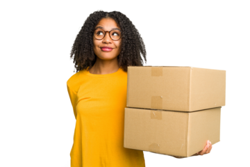 Young african american woman moving to other house while picking up a box full of things isolated dreaming of achieving goals and purposes