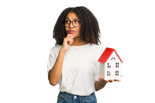 Young african american woman moving to a new home while picking up a box full of things isolated looking sideways with doubtful and skeptical expression.