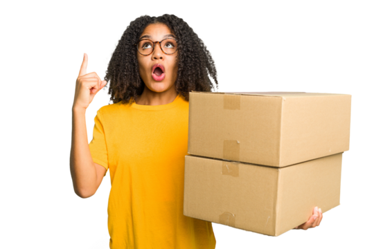 Young african american woman moving to other house while picking up a box full of things isolated pointing upside with opened mouth.