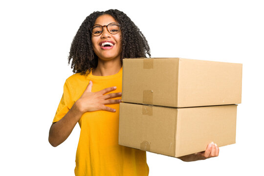 Young african american woman moving to other house while picking up a box full of things isolated laughs out loudly keeping hand on chest.