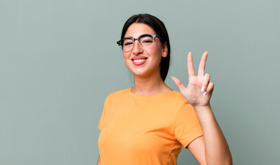 smiling and looking friendly, showing number three or third with hand forward, counting down