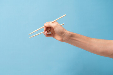 hand holds wooden asian food chopsticks