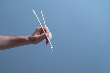 hand holds wooden asian food chopsticks