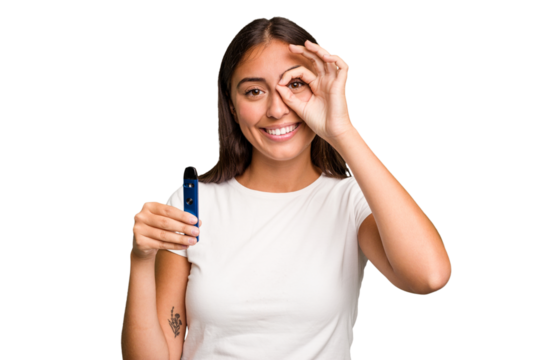 Young caucasian woman holding a electronic cigarette excited keeping ok gesture on eye.