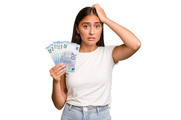 Young caucasian woman holding a banknotes isolated being shocked, she has remembered important...