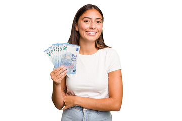 Young caucasian woman holding a banknotes isolated laughing and having fun.