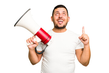 Young caucasian man holding a megaphone isolated pointing upside with opened mouth.