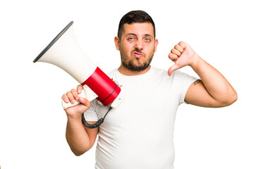 Young caucasian man holding a megaphone isolated showing a dislike gesture, thumbs down. Disagreement concept.