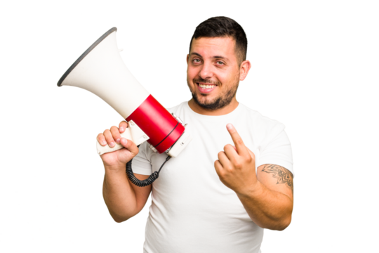 Young caucasian man holding a megaphone isolated pointing with finger at you as if inviting come closer.