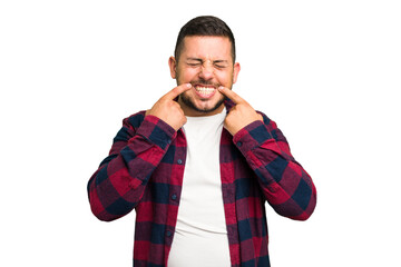 Young caucasian man isolated smiles, pointing fingers at mouth.