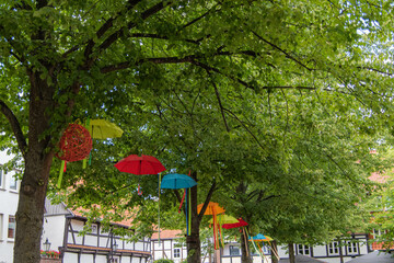 Bunte Schirme und Bänder hängen in Bäumen