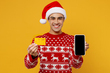 Merry fun young man wears red xmas sweater Santa hat posing use blank screen mobile cell phone...