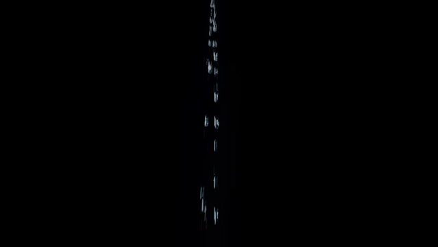 A thin jet of water from drops fall on a black background. Overlay template.