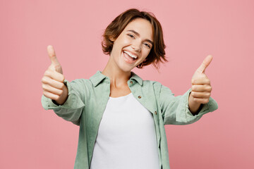 Young happy smiling cheerful fun cool woman 20s she wear mint shirt white t-shirt show thumb up...