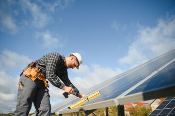 Professional worker installing solar panels on the metal construction, using different equipment, wearing helmet. Innovative solution for energy solving. Use renewable resources. Green energy.