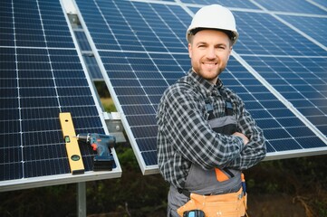 A handyman standing on the rooftop with solar panels and smiling at the camera.