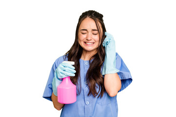 Young cleaner caucasian woman isolated on green chroma background covering ears with hands.