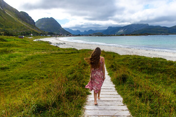 beautiful long-haired girl in a dress walks along the famous ramberg beach (rambergstranda) on the...