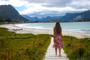 beautiful long-haired girl in a dress walks along the famous ramberg beach (rambergstranda) on the...