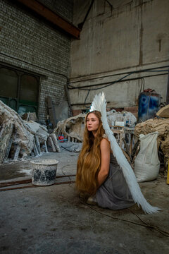 A girl in the image of an angel sits in an architectural workshop.