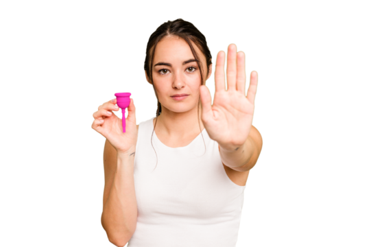 Young caucasian woman holding menstrual cup isolated on green chroma background standing with outstretched hand showing stop sign, preventing you.