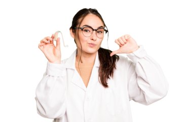 Young otorhinolaryngologist holding hearing aid isolated on green chroma background feels proud and self confident, example to follow.