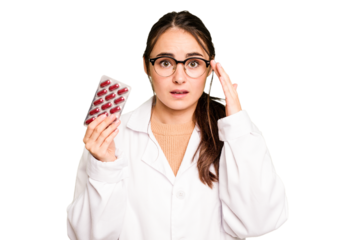 Young pharmacist woman holding a pills isolated on green chroma background showing a disappointment gesture with forefinger.