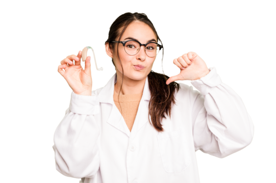 Young otorhinolaryngologist holding hearing aid isolated on green chroma background feels proud and self confident, example to follow.