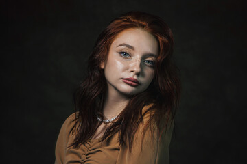 Portrait of a beautiful red-haired girl on a dark background