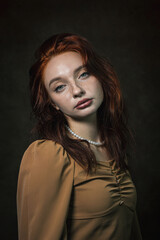 Fototapeta premium Portrait of a beautiful red-haired girl on a dark background