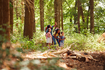 Naklejka na ściany i meble Family With Backpacks Hiking Or Walking Through Woodland Countryside