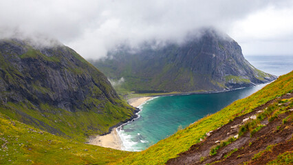 Naklejka na ściany i meble panoramic view of a famous kvalvika beach on the lofoten islands in norway; the famous beach surrounded by massive rugged mountains