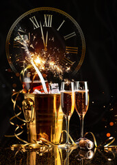 Happy New Year! A golden bucket with champagne, two glasses and a golden serpentine against the...
