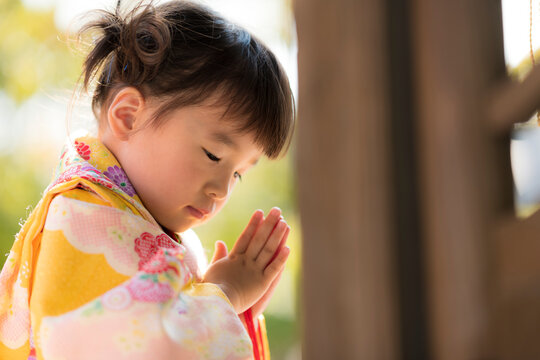 神社で七五三のお参りをする3歳の着物を着た女の子