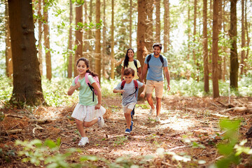 Family With Backpacks Hiking Or Walking Through Woodland Countryside