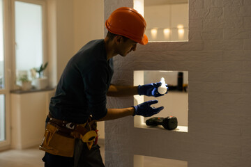 Electrician installs lamp lighting and spot loft style