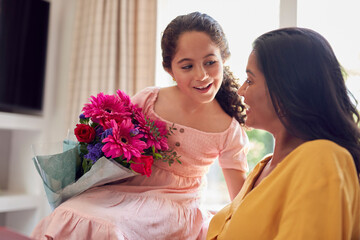 Daughter Giving Mother Bunch Of Flowers For Birthday Or Mothers Day At Home