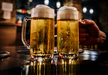 man holds a glass of beer in his hand at the bar or pub