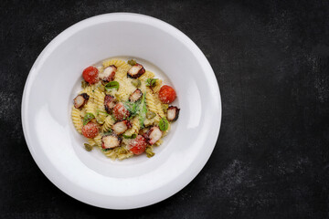 Pasta with octopus, tomatoes and Parmesan cheese, on a plate